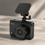 Black car dashboard camera with magnetic phone mount on a beige background