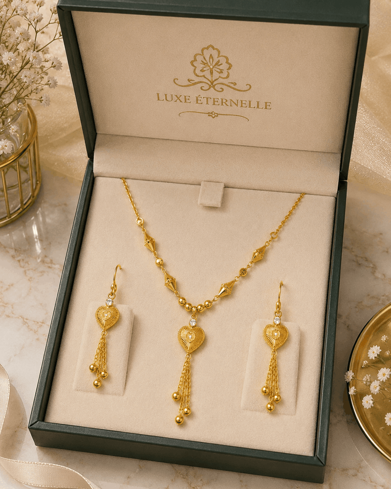 Gold necklace and earrings set in a 'LUXE ÉTERNELLE' box on a marble surface.