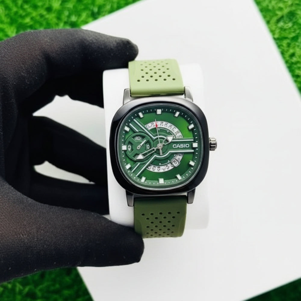Green watch with a white strap held by a gloved hand on a grassy background At Aezoon