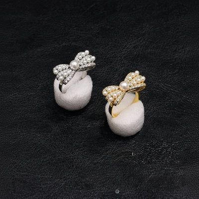 Pair of earrings with bow designs on a dark background At Aezoon
