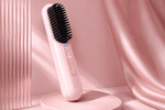 Pink hairbrush with black bristle head on a pink stand against a pink curtain background