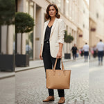 Woman in a white blazer and black pants holding a beige tote bag on a city street. At Aezoon