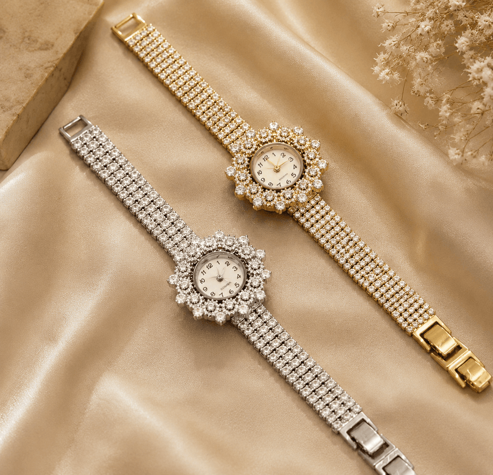 Two ornate wristwatches, one gold and one silver, on a beige fabric background.