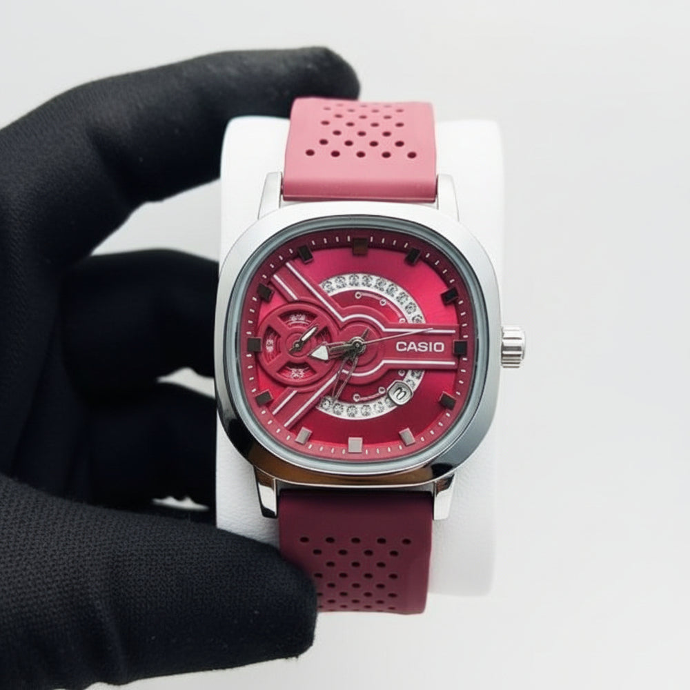 Watch with a red face and pink strap held by a hand against a white background At Aezoon