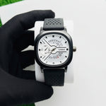Watch with black strap and white face held by a gloved hand on a light background At Aezoon