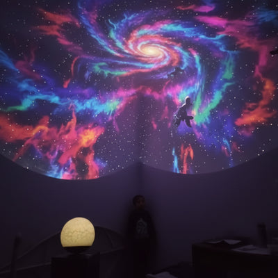 Colorful spiral galaxy projection on a dark wall with a spherical light fixture below.